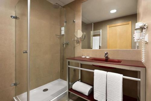 bagno con doccia, lavandino e specchio di Ramada by Wyndham Madrid Getafe a Getafe