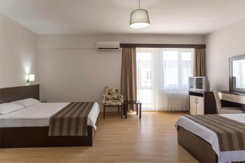 ein Hotelzimmer mit zwei Betten und einem Fernseher in der Unterkunft Troas Beach Hotel in Tavaklı