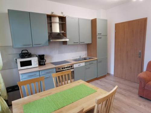 eine Küche mit einem Holztisch und eine Küche mit blauen Schränken in der Unterkunft Ferienwohnung "Zur Kleinbahn" in Zittau