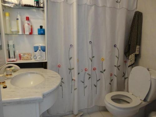 a bathroom with a shower curtain with a toilet and a sink at Long Beach - casi un spa in Punta del Este