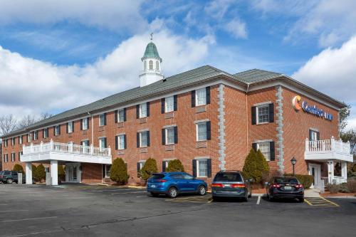 un gran edificio de ladrillo rojo con coches aparcados en un aparcamiento en Comfort Inn Auburn-Worcester, en Auburn