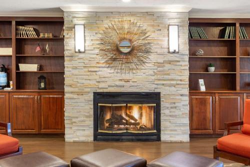 a living room with a stone fireplace with a clock at Comfort Inn Auburn-Worcester in Auburn