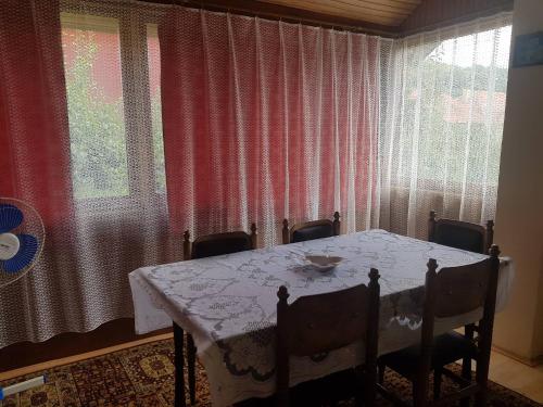 a dining room table and chairs with a table and curtains at Vila Happy Story in Knjazevac.