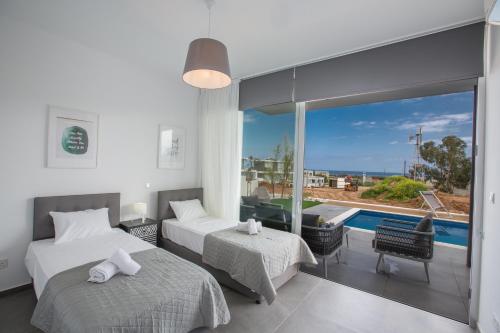een slaapkamer met 2 bedden en een balkon met een zwembad bij Villa Naya in Protaras