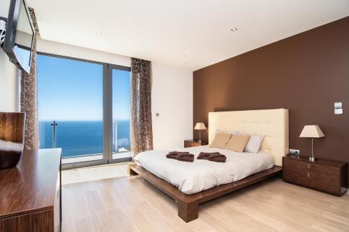 a bedroom with a large bed and a large window at Luxo & Conforto in Calheta