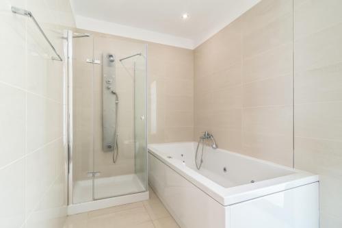 a white bathroom with a shower and a tub at Luxo & Conforto in Calheta