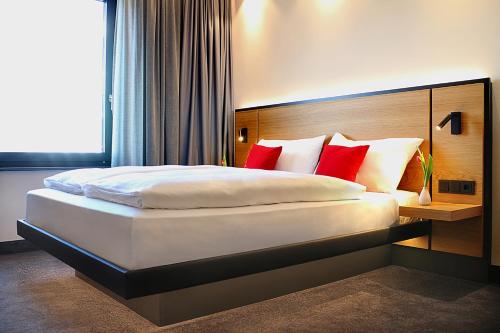 a bedroom with a large bed with red pillows at GINN City and Lounge Ravensburg in Ravensburg