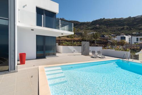a villa with a swimming pool and a house at Luxo & Conforto in Calheta