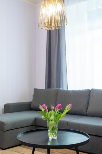 a vase with pink flowers on a table in front of a couch at Südalinna apartment in Kuressaare