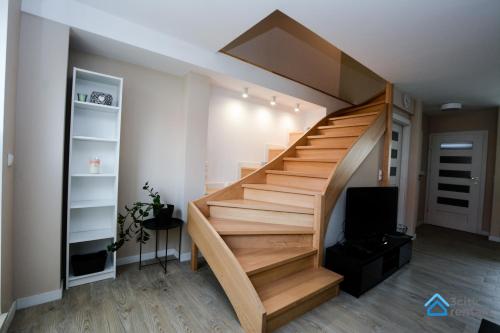 a wooden staircase in a room with a tv at Dwupoziomowy Apartament 3city w Gdyni z Biurkiem i Balkonem by Noclegi Renters in Gdynia