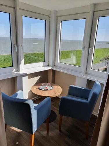 a room with three windows and a table and chairs at Nordseehotel Wilhelmshaven in Wilhelmshaven
