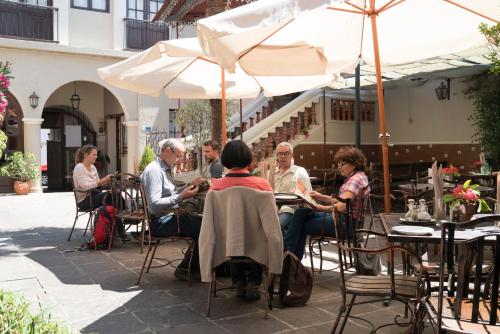 a group of people sitting at an outdoor table with an umbrella at Hotel Boutique La Posada in Sucre