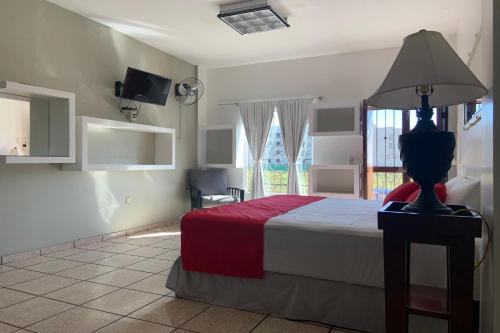 a bedroom with a bed with a lamp and a window at Hotel Posada Doña Rubino in Mazatlán