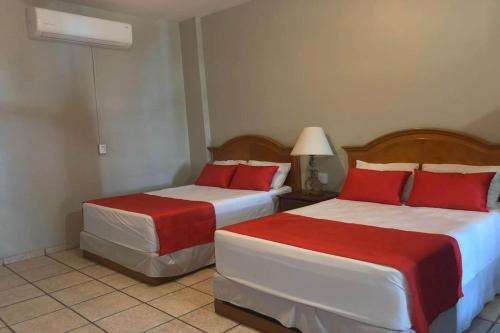 a hotel room with two beds with red pillows at Hotel Posada Doña Rubino in Mazatlán