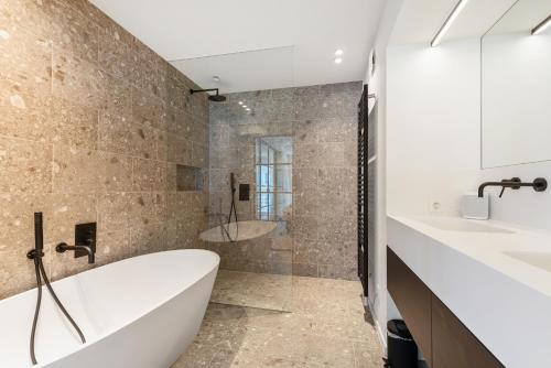 ein Bad mit einer Badewanne, 2 Waschbecken und einer Dusche in der Unterkunft Hyper-Luxeappartement, zeezicht, centrum, airco, optie hotelservices in Ostende