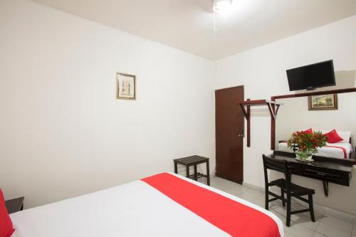um quarto com uma cama e uma secretária com uma televisão em Hotel Angel em León
