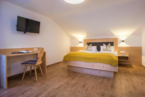 a bedroom with a bed and a desk and a television at Badererhof Christine Wechselberger in Stumm