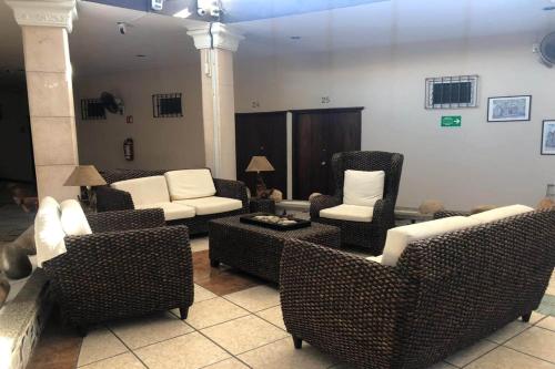 a living room with wicker chairs and couches at Hotel Posada Doña Rubino in Mazatlán