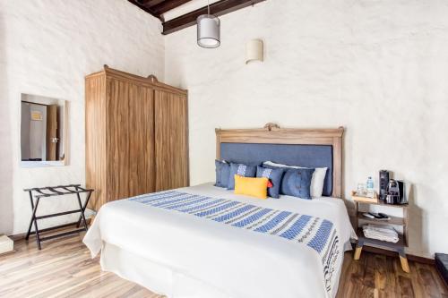 a bedroom with a large bed with blue and yellow pillows at Hotel Milagro, Puebla Centro in Puebla