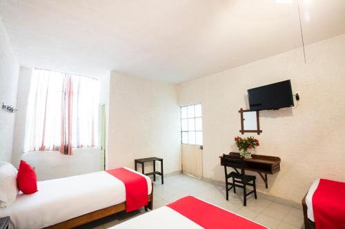 una camera d'albergo con due letti e una televisione di Hotel Angel a León