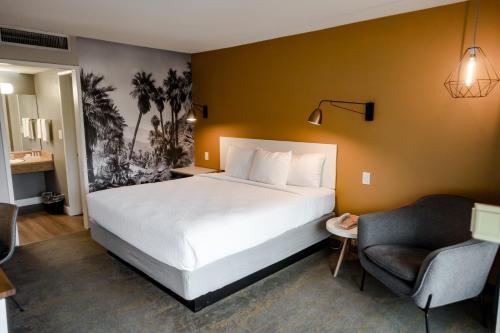 Habitación de hotel con cama y silla en Vagabond Motor Hotel - Palm Springs en Palm Springs
