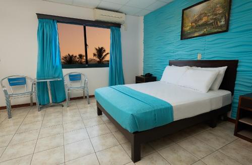 1 dormitorio con cama y pared azul en Hotel Puntarenas Beach en Puntarenas