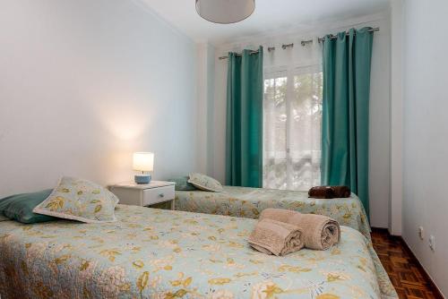 a bedroom with two beds with green curtains and a window at Senna Apartment in Lisbon