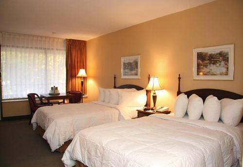 a hotel room with two beds and a desk at Mansion View Inn & Suites in Springfield