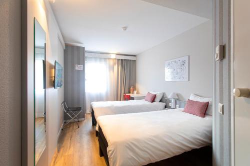 um quarto de hotel com duas camas e uma janela em Ibis Valencia Alfafar em Alfafar