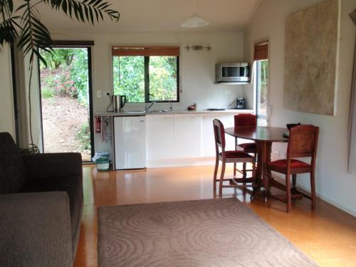 a kitchen and living room with a table and chairs at Wharepuke Subtropical Accommodation in Kerikeri