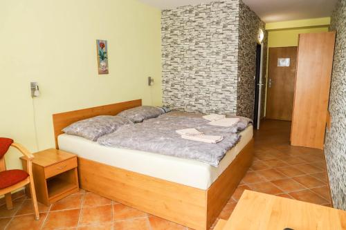 a bedroom with a bed and a brick wall at Hotel Zátoka in Senec