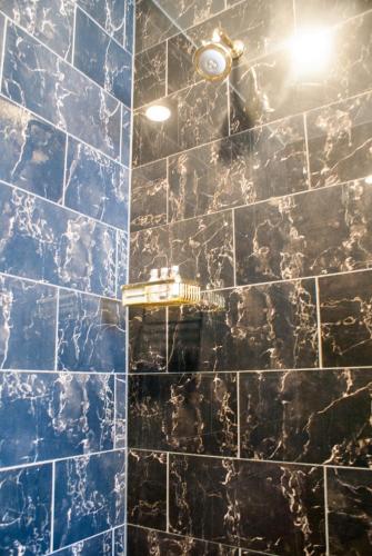 a bathroom with a blue tiled wall with a light at Audubon Cottages in New Orleans