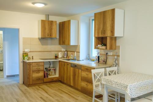 a kitchen with wooden cabinets and a table and a counter at Livi Apartman in Szentantalfa
