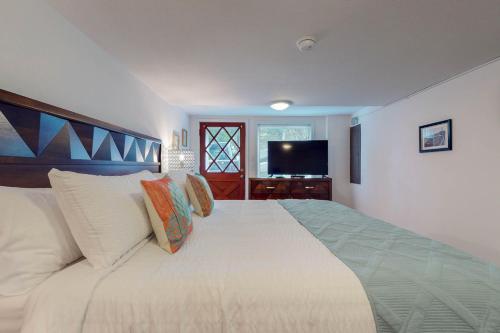 a bedroom with a large white bed and a television at Abalone Rose in Newport