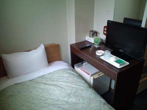 sypialnia z łóżkiem i biurkiem z telewizorem w obiekcie City Inn Nishi Tanabe / Vacation STAY 78427 w Osace