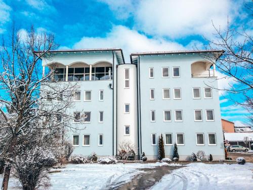 a white building with snow in front of it at Hotel Schwertfirm in Karlsfeld