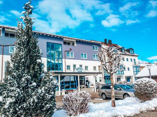 un árbol de Navidad cubierto de nieve frente a un edificio en Hotel Schwertfirm, en Karlsfeld