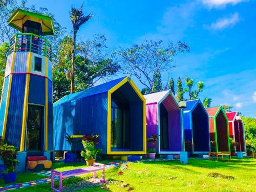 a row of colorful beach huts in a yard at Lanzones Cabana in Mambajao