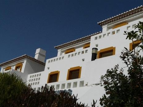 a white building with yellow windows on top of it at Apartamentos Os Descobrimentos in Burgau