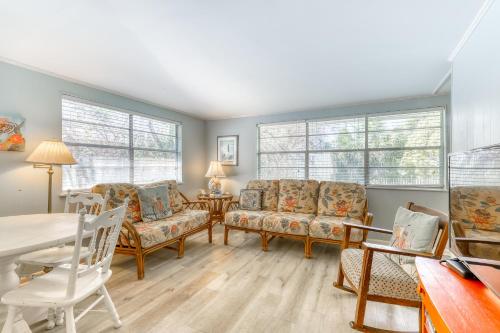a living room with chairs and a table and windows at Beach Cottage on Jones in Tybee Island