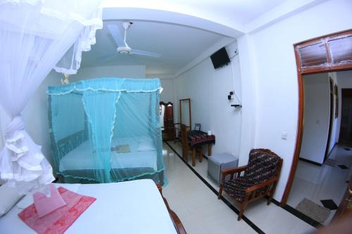 a room with a bed and chairs and a mirror at Sunnyplace Guest Mirissa in Mirissa
