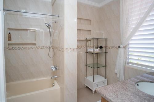 a bathroom with a shower and a tub and a sink at Edgewater Beach Villa - Beach Front, Close to All Attractions in St Mary