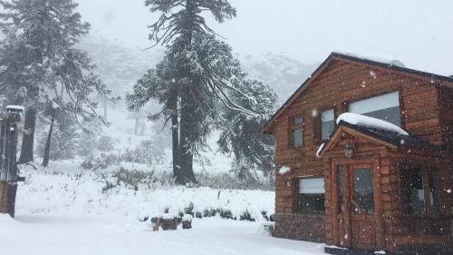 a house covered in snow in a yard at Lodge Tikilen Caviahue in Caviahue