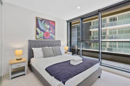 a bedroom with a bed and a large window at YARRA · YARRA Toorak Rd & Chapel St. Pool, Gym & Parking in Melbourne