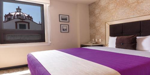 a bedroom with a purple and white bed and a window at Mansion Azul Cholula in Cholula