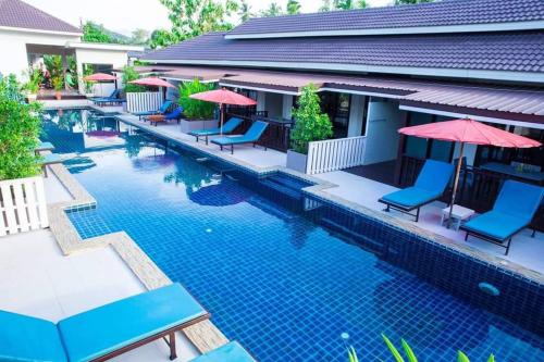 a swimming pool with blue chairs and umbrellas at The Florist Resort in Mae Nam