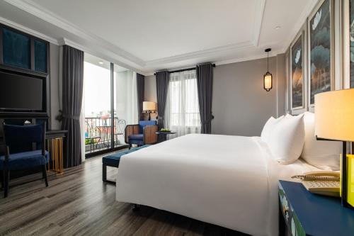 um quarto de hotel com uma grande cama branca e uma secretária em Solaria Hanoi Hotel em Hanói