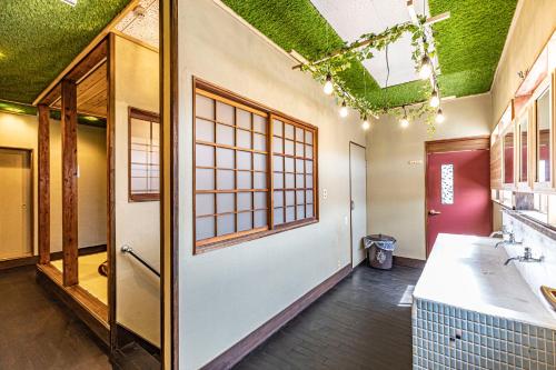 La salle de bains est pourvue d'un plafond vert et d'une porte. dans l'établissement 47HOSTEL, à Wadomari