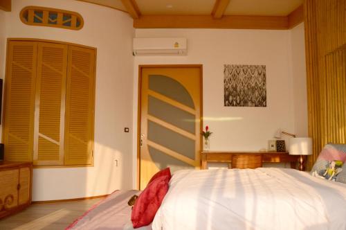 a bedroom with a bed with white sheets and a window at Pannana Cha-am in Cha Am