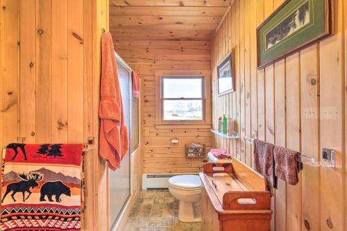 a bathroom with a toilet and a wooden wall at Family-Friendly Troy Getaway with Furnished Deck! in Unity